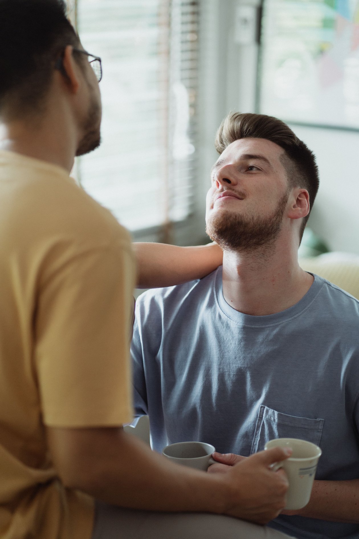 A man holding a coffee mug while listening to his partner