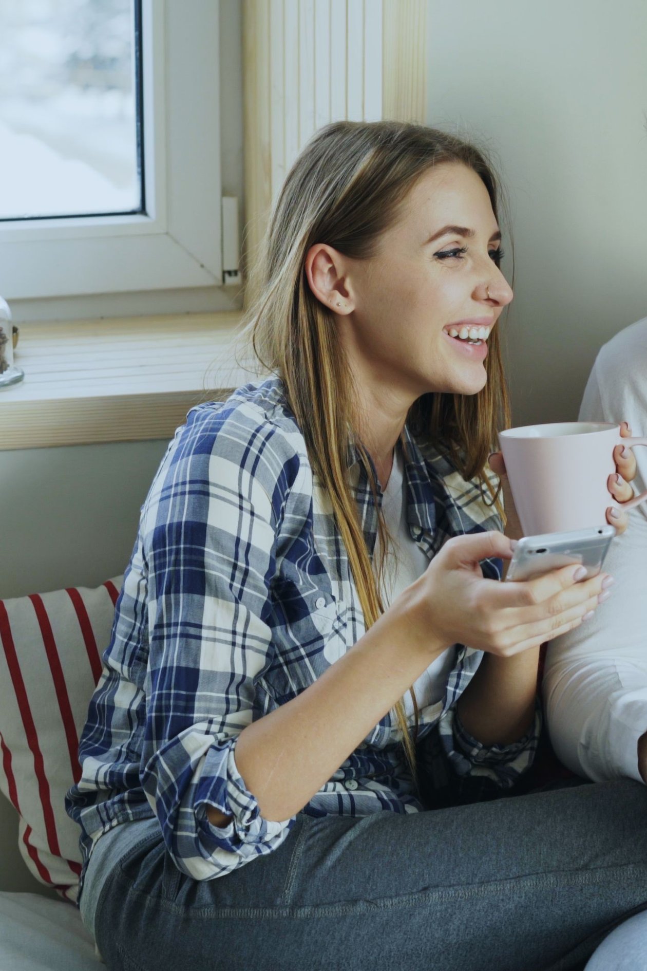 A woman laughing with her partner while holding a coffee mug