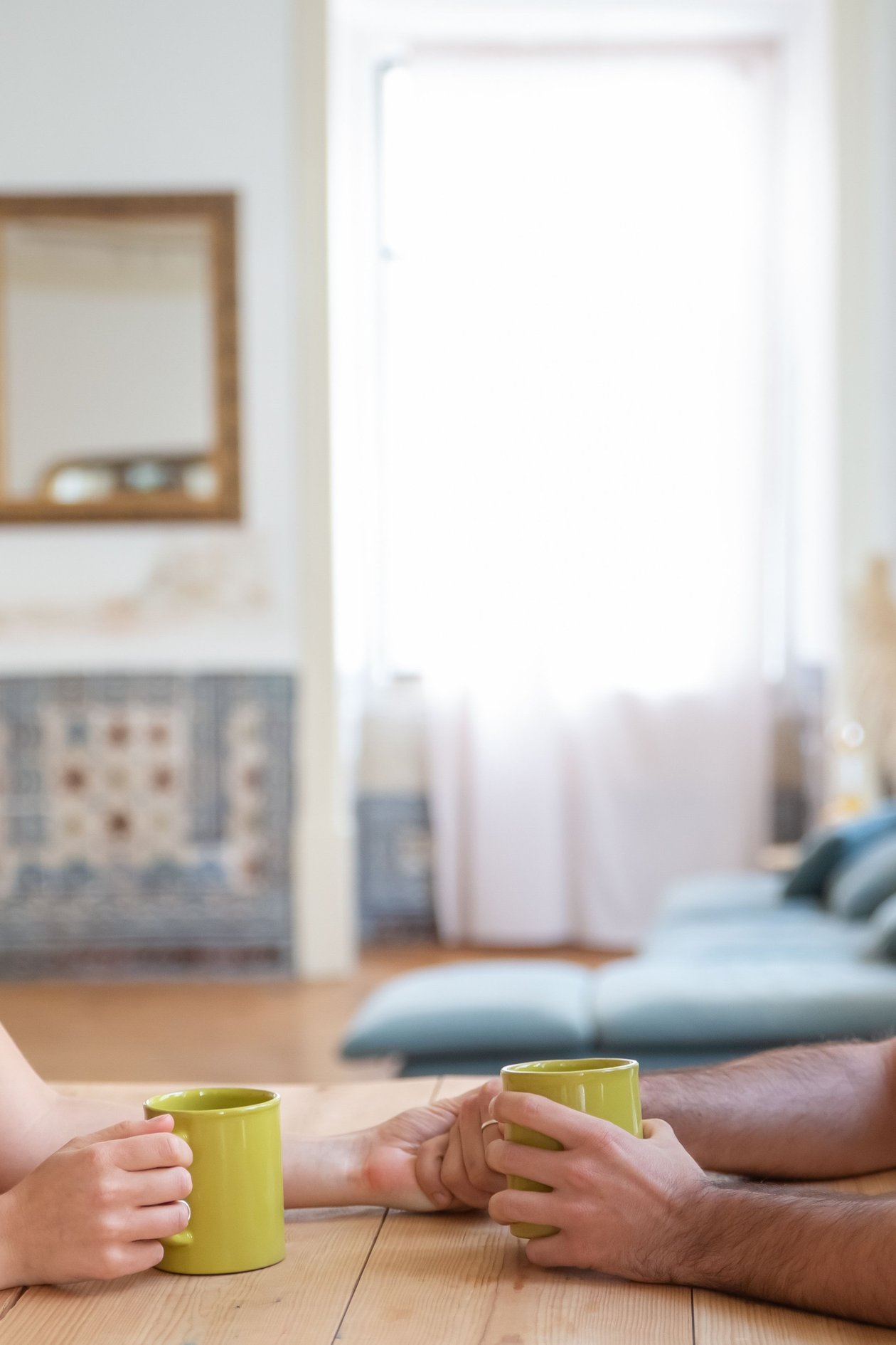 A couple holding hands over mugs of coffee at a table