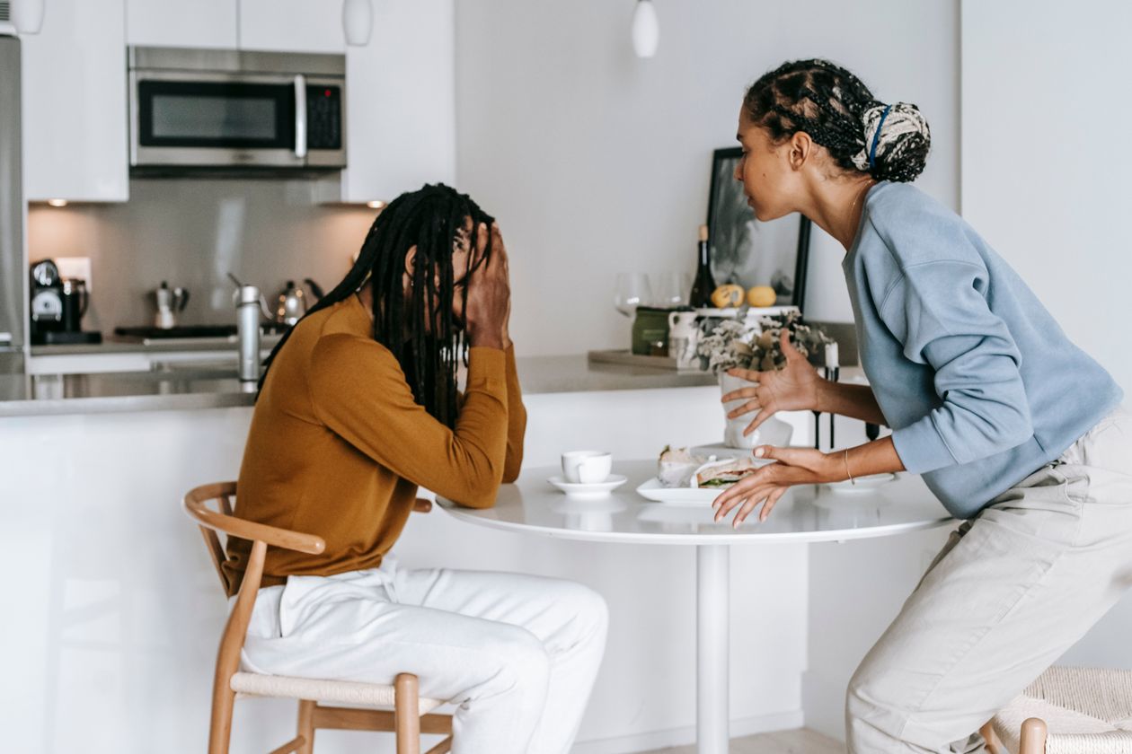 A man overwhelmed with his head in his hands while his partner speaks